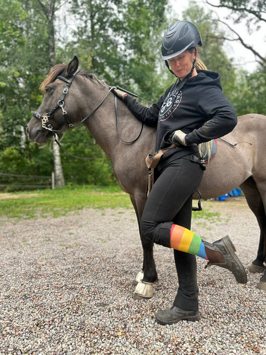 Tjej står och visar Reidsokkar ridstrumpor i merinoull färg Pride